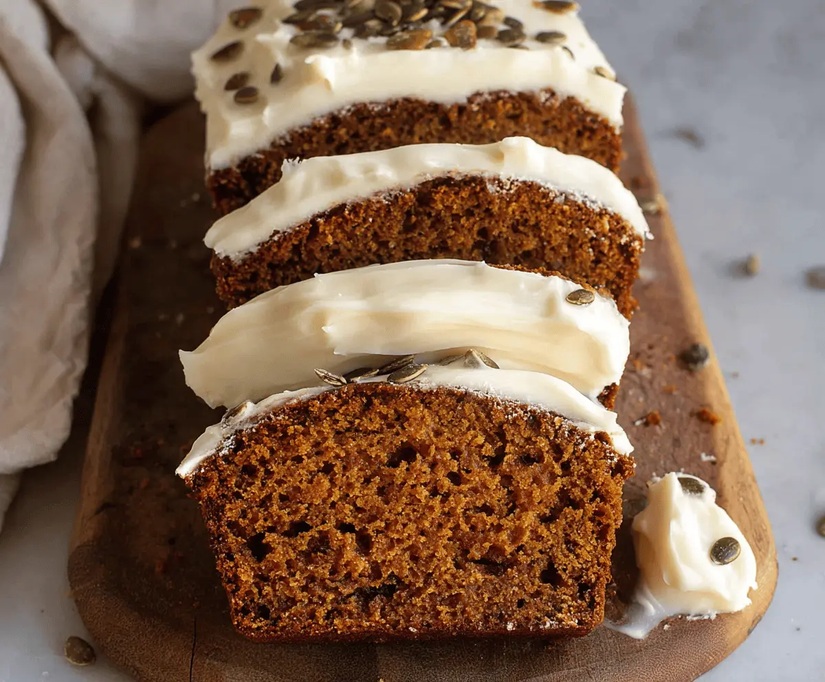 Delicious homemade pumpkin bread topped with creamy cream cheese frosting, garnished with fresh olives and thyme herbs