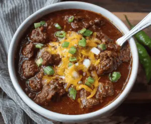 Spicy Texas Style No Bean Chili topped with shredded cheese and fresh herbs in a rustic bowl
