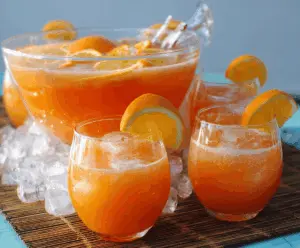 Colorful Orange Party Punch in a clear glass pitcher with fresh orange slices and ice, perfect for celebrations