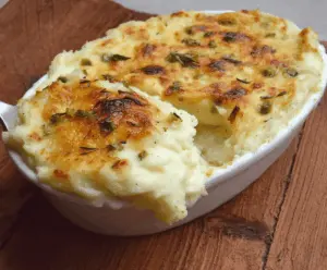 Creamy garlic mashed potato casserole topped with golden-brown crust, perfect for comfort food lovers.