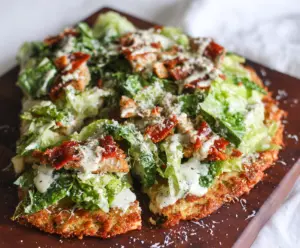 Delicious Chicken Crust Caesar Salad Pizza topped with fresh romaine lettuce and Caesar dressing.