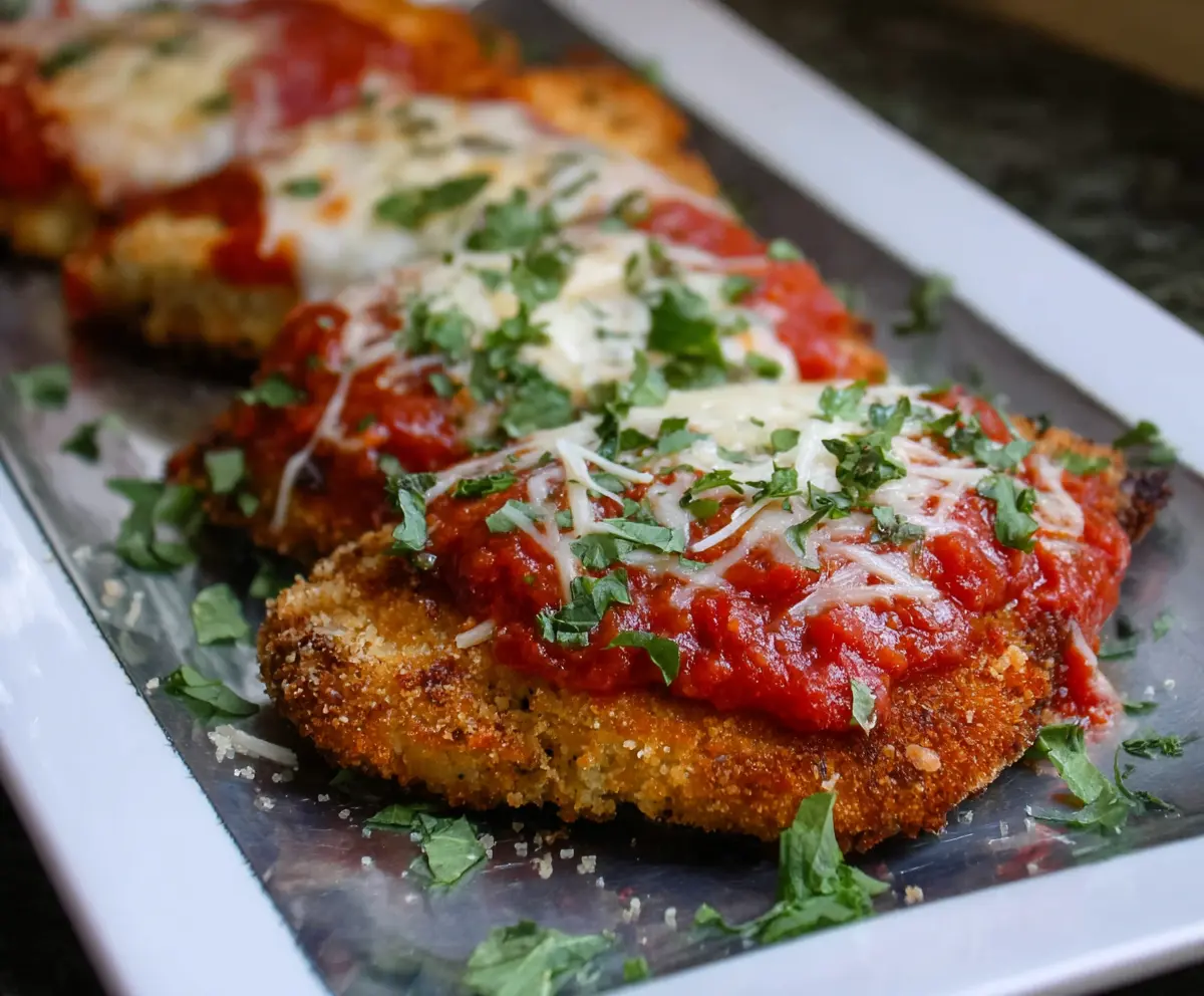 Crispy panko-breaded pork parmigiana topped with melted cheese on a plate